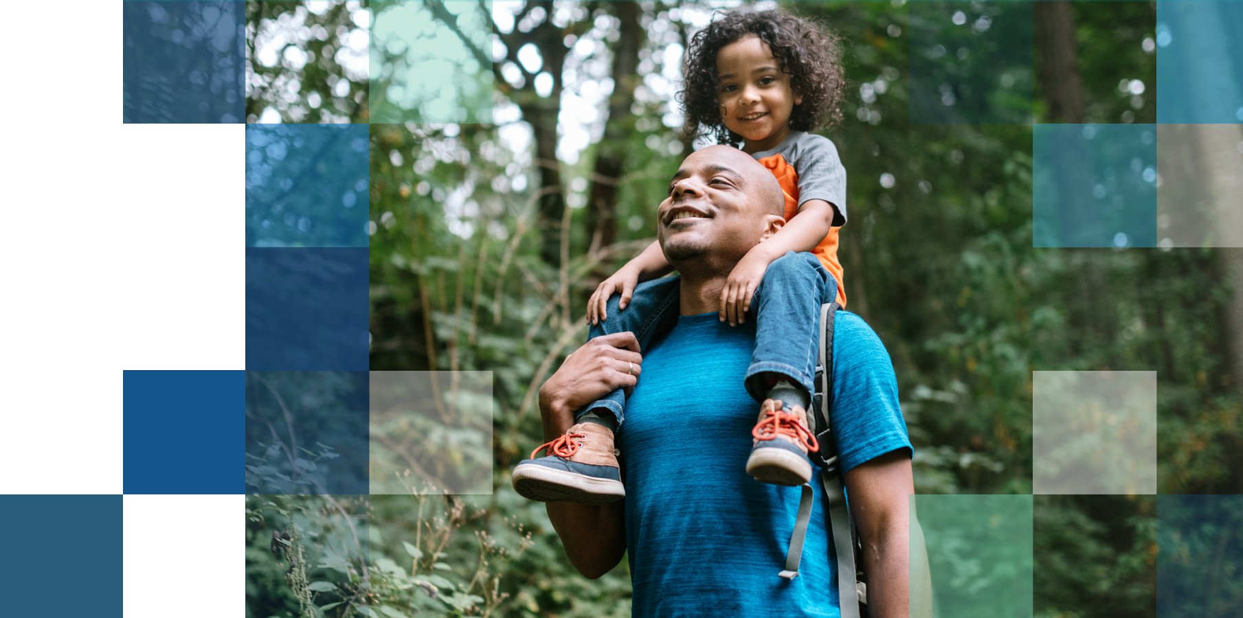 Father with child on his shoulders in a lush green forest on a hike.